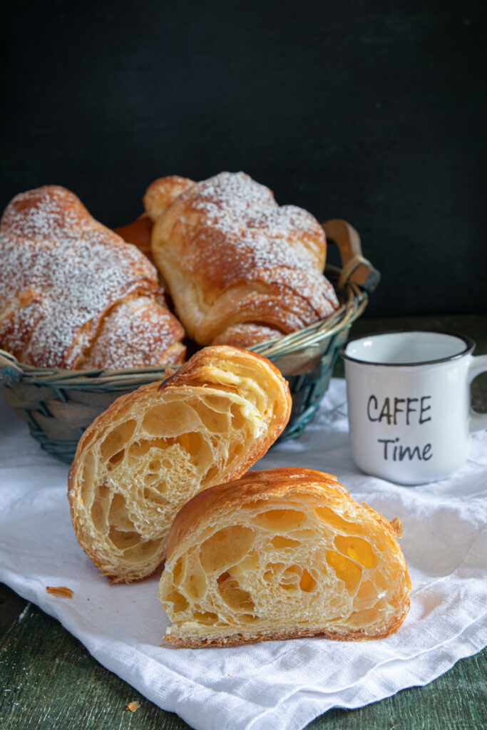 Biscuits in a basket with one cut in half on a white napkin.