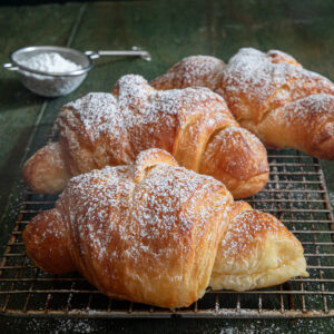 Three cornetti on a wire rack.