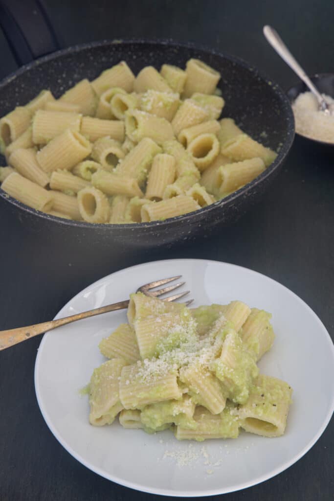 Broccoli pasta in the pan and some on a white plate.