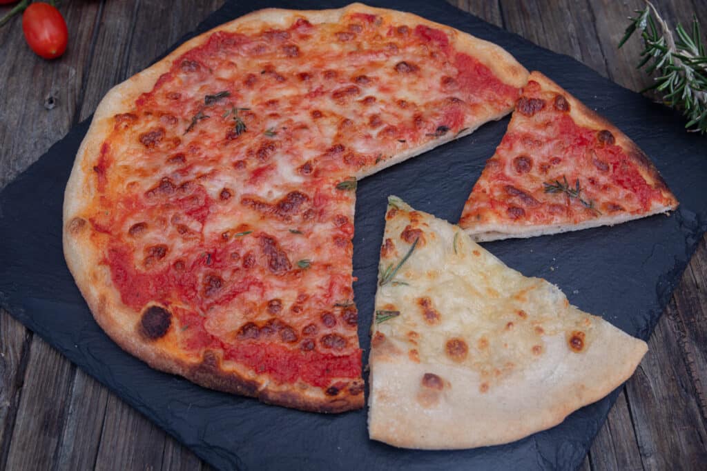 White and red pizza on a black board.