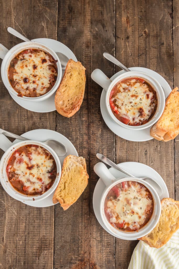Four soup bowls on a wooden board.