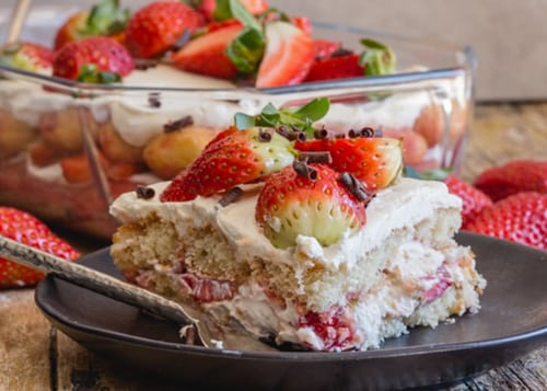 Strawberry tiramisu in a pan and a slice on a black plate.