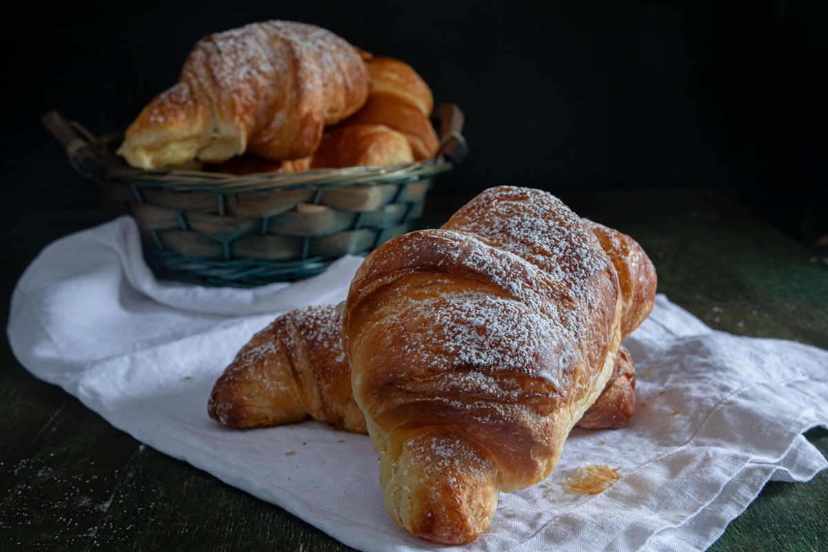 Cornetti in a basket and two on a napkin.