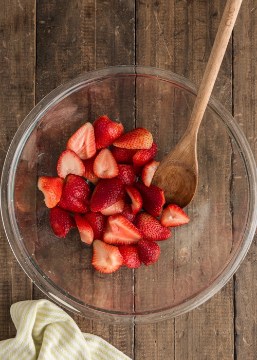 Mixing the strawberries in a glass bowl.