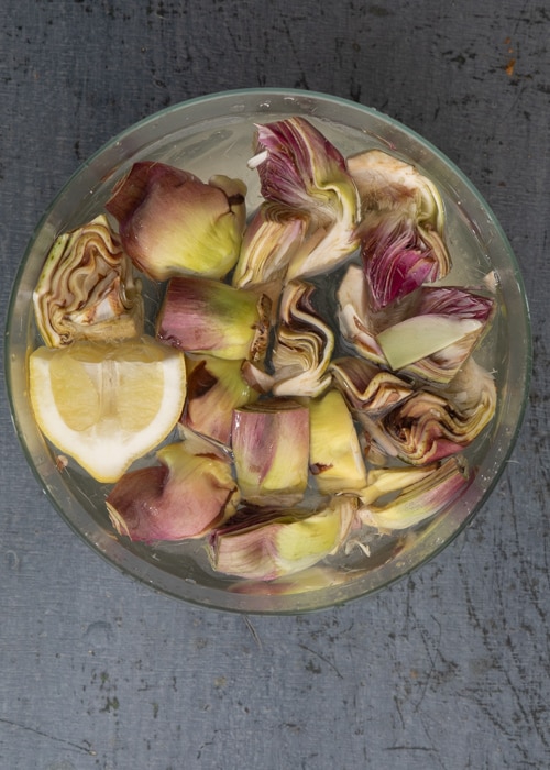 Soaking the artichokes in a glass bowl of water.
