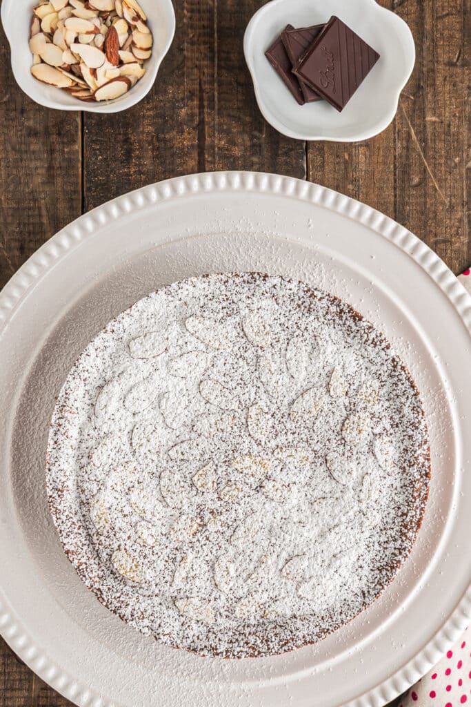 The baked cake dusted with powdered sugar on a white plate.
