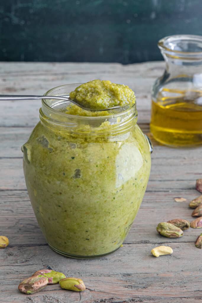 Pistachio pesto on a spoon and in the jar.