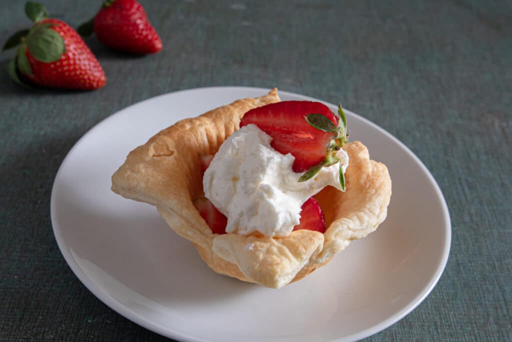 A strawberry cheesecake cup on a white plate.