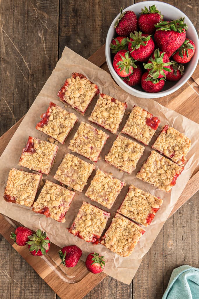 Cut strawberry crumb bars on parchment paper.