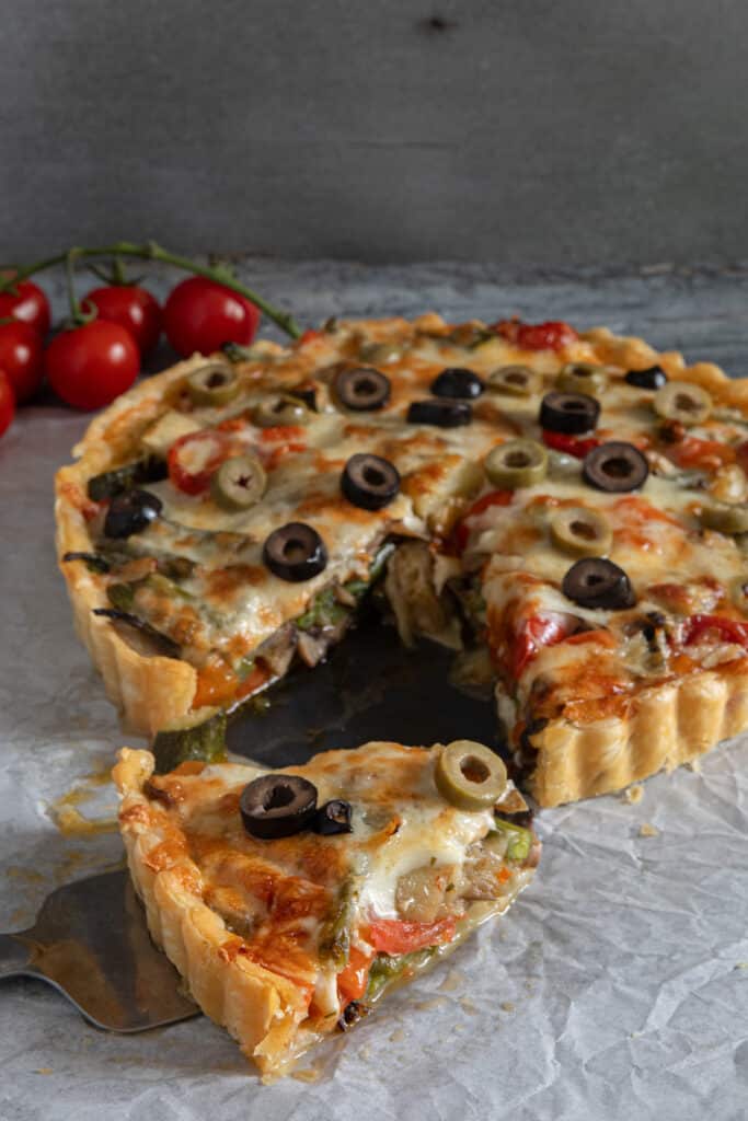Vegetable tart with a slice cut.