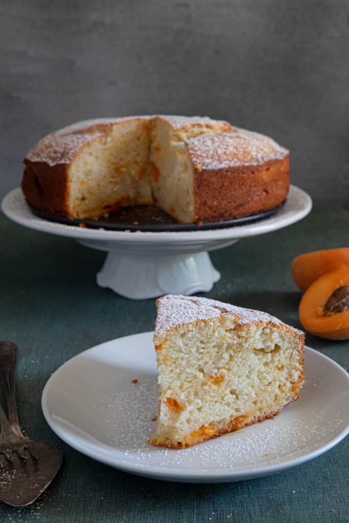 Apricot cake on a white plate with a slice on a small plate.