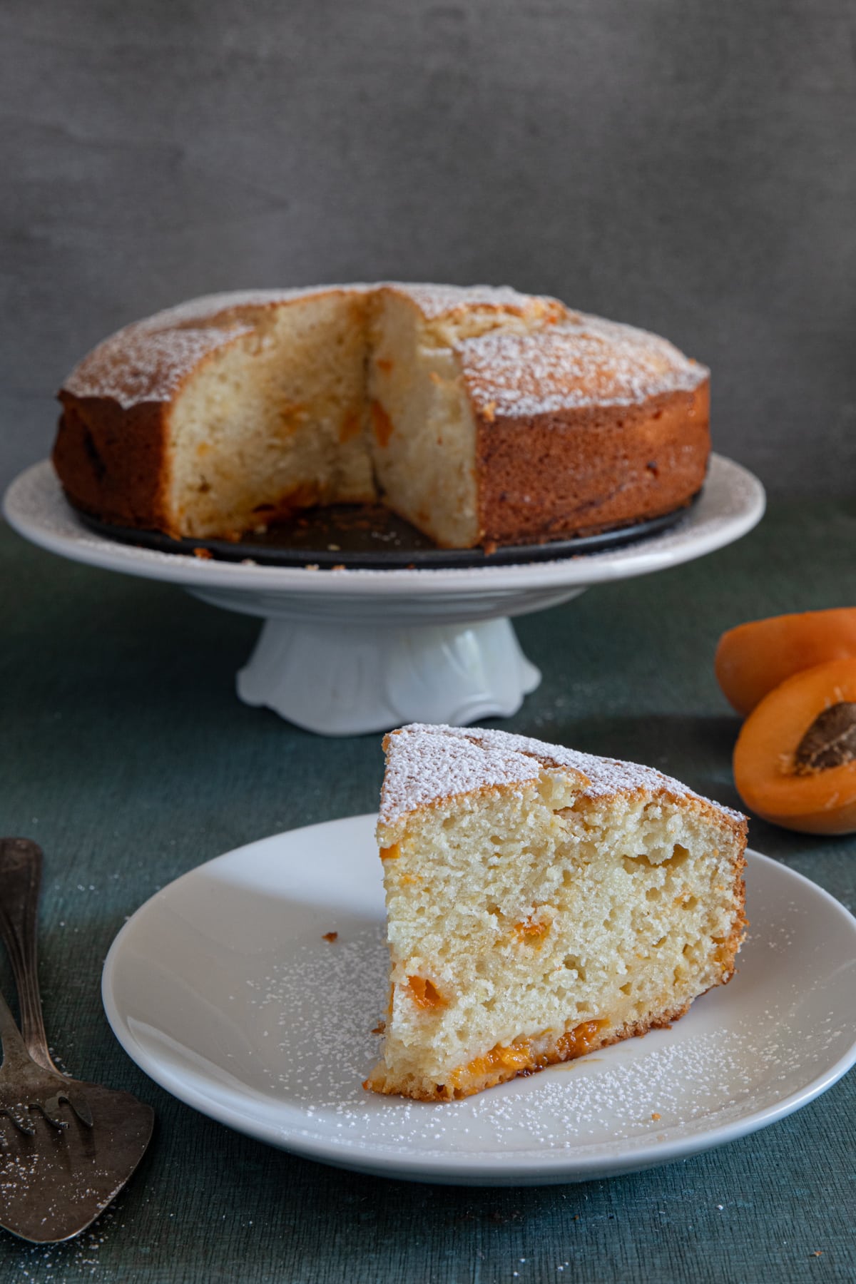 Apricot cake on a white plate with a slice on a small plate.