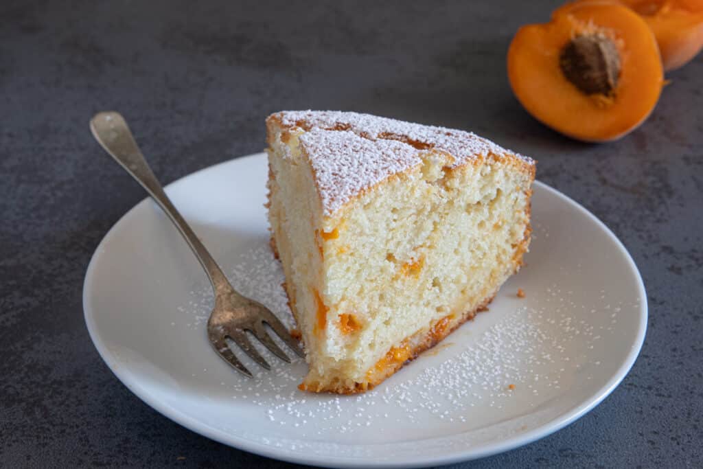 A slice of cake on a white plate with a silver fork.