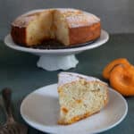 Apricot cake on a white plate with a slice on a small plate.