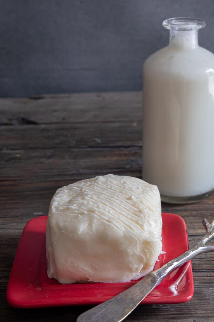 Homemade butter on a red dish and a bottle of buttermilk.