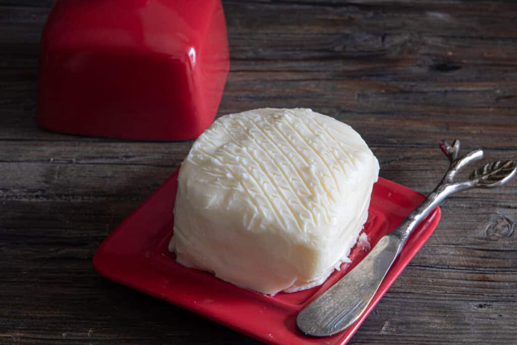 Butter in a red dish with a silver knife.
