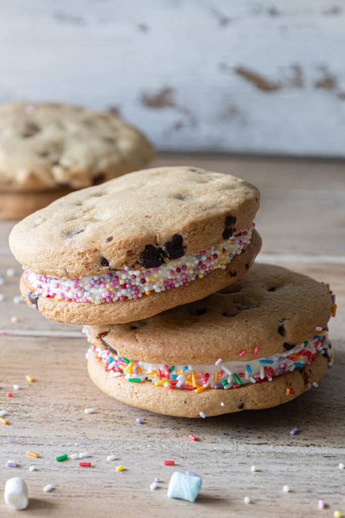 Two sandwich cookies stacked with cookies in the back ground.