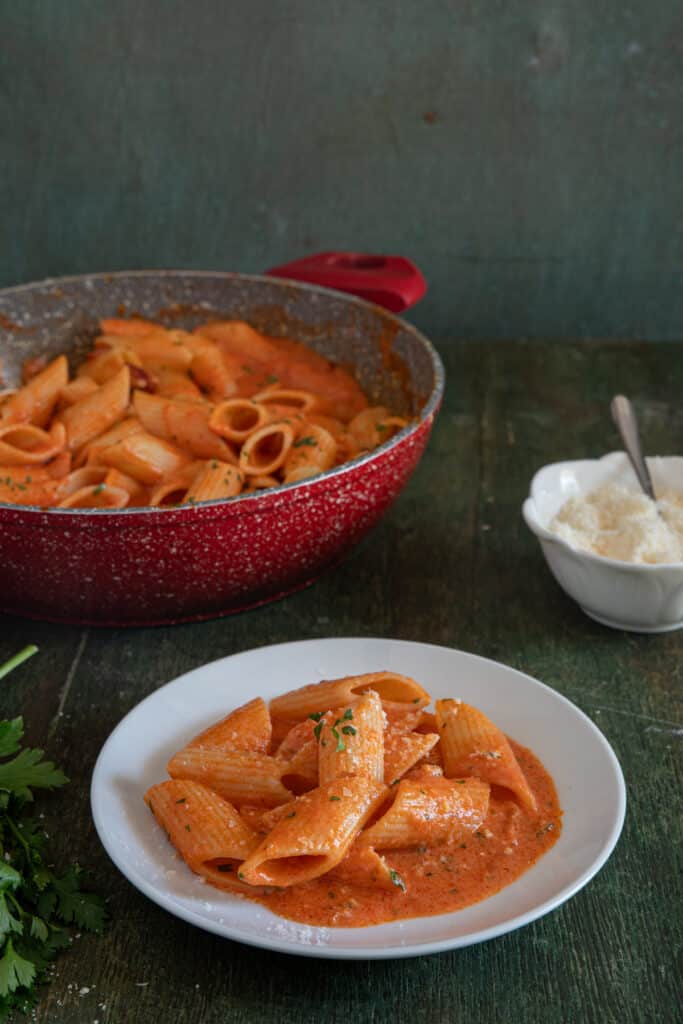 Penne alla vodka in the pan and some on a white plate.