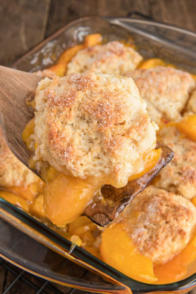 The peach cobbler in the pan and one on a spoon.