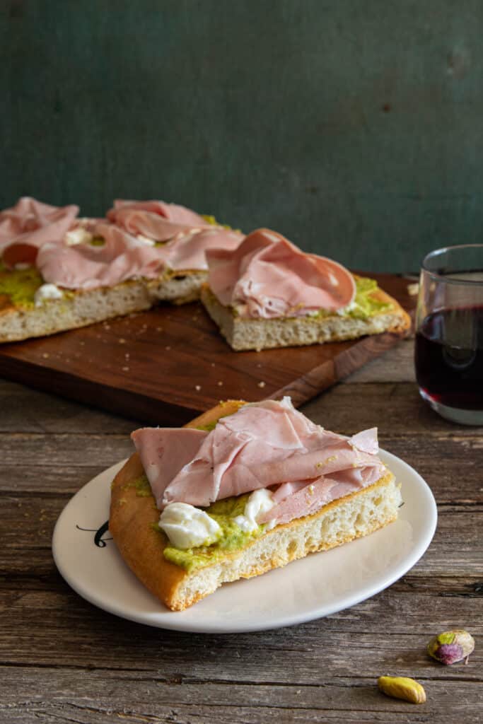 Schiacciata on a board with a slice on a white plate.