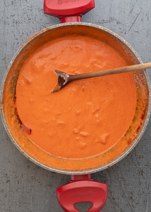 Adding the cream to the sauce in the pan.