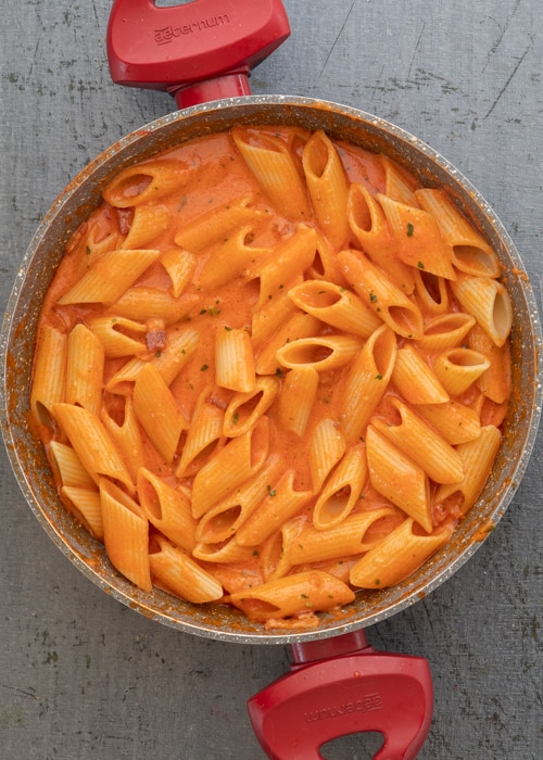 The pasta added to the sauce in the pan.