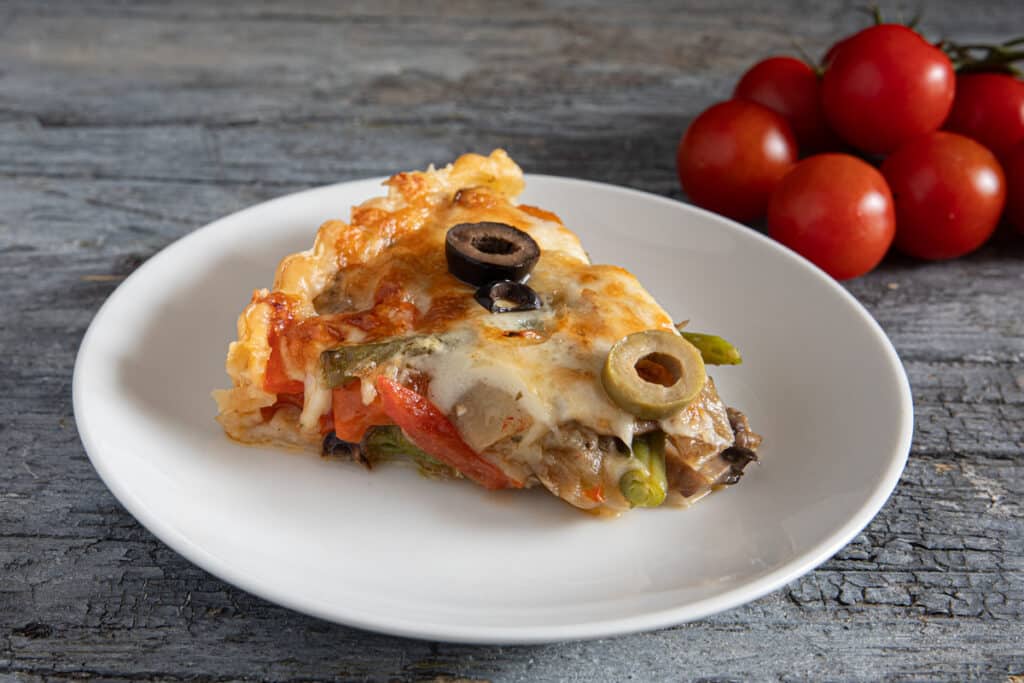 A slice of vegetable tart on a white plate.