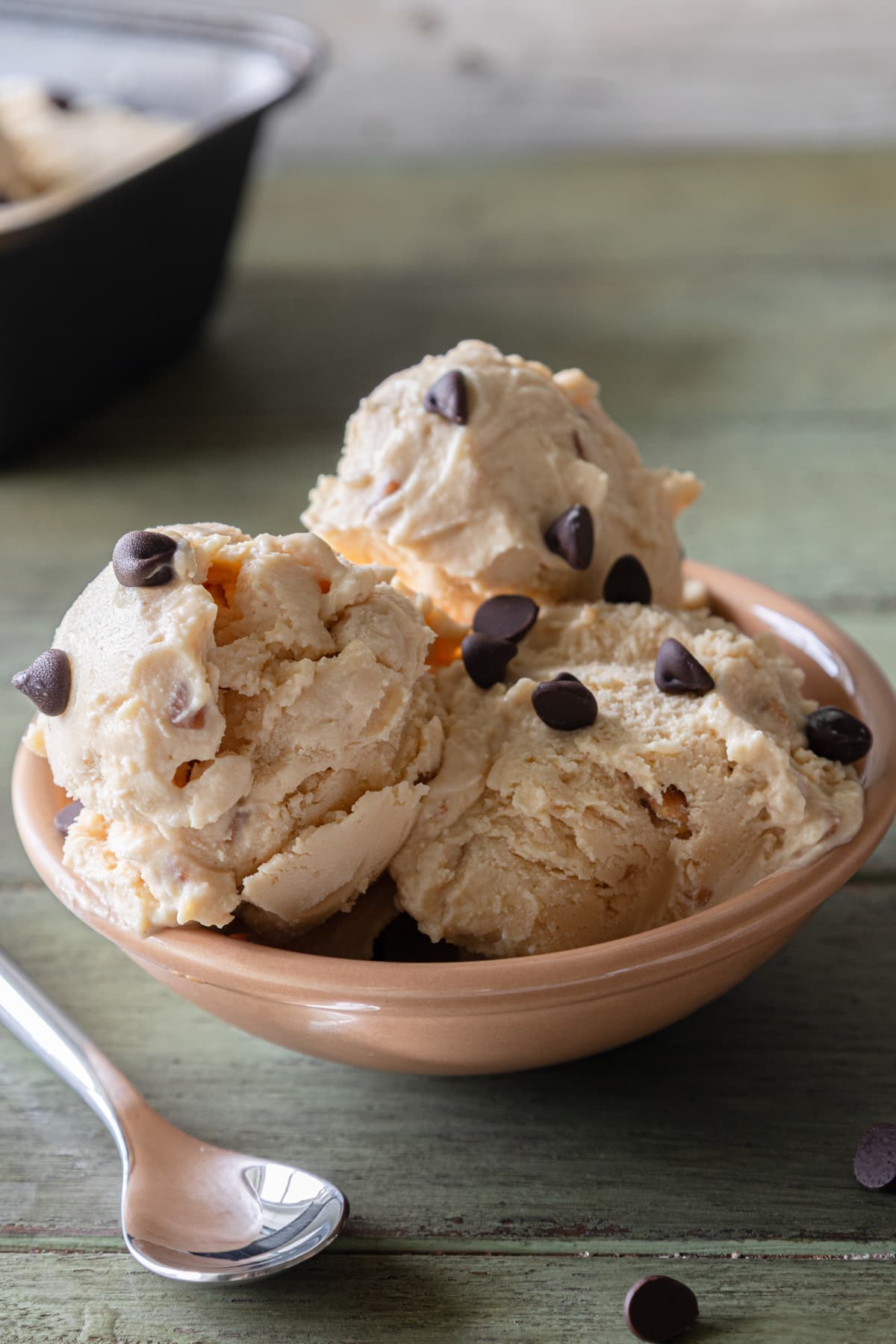Three scoops of peanut butter Ice cream in a bowl with a spoon.