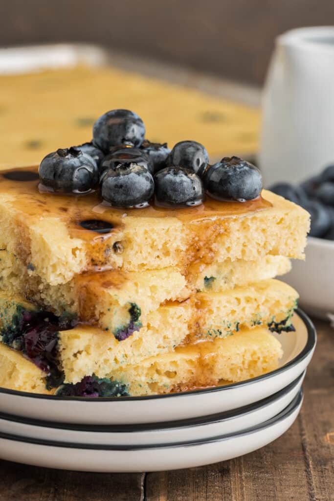 Four pancakes stacked with syrup and blueberries.
