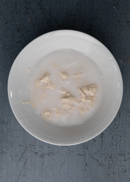 Mixing the lievito madre and water in a bowl.