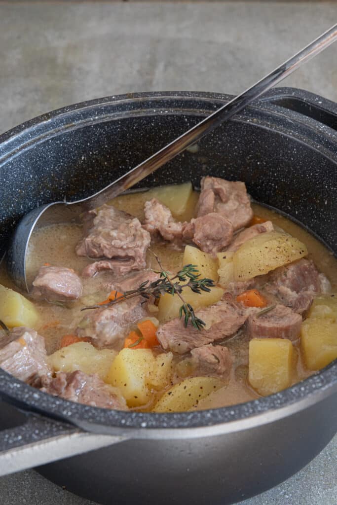 Beef and potato stew in a black pot.