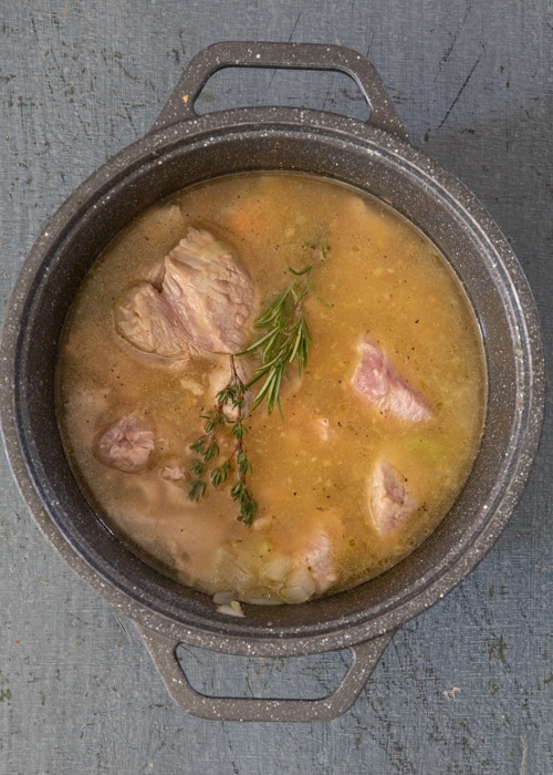 Adding the broth and spices to the pot.