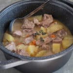 Beef and potato stew in a black pot.