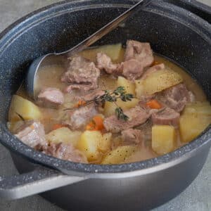 Beef and potato stew in a black pot.