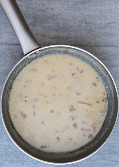 The cream sauce and pancetta in the pan.