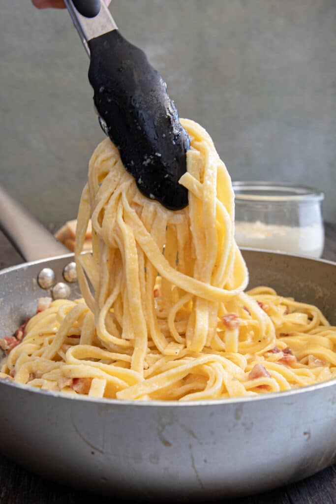 The pasta in tongs and the pan.