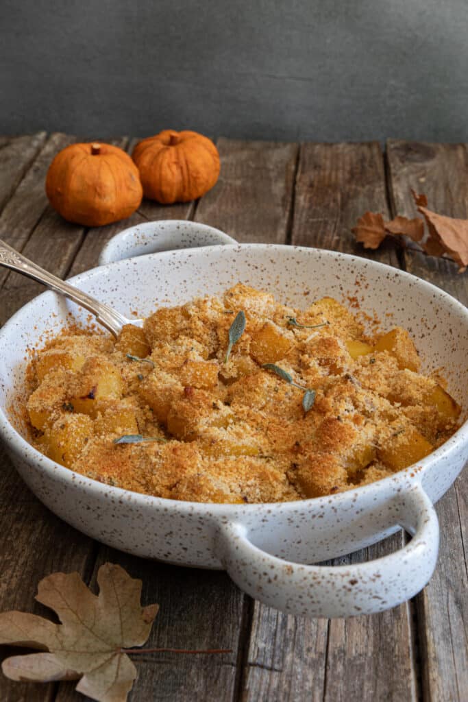 The squash gratin in a white baking dish with a spoon.