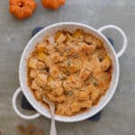 Squash gratin in a white dish with a spoon.