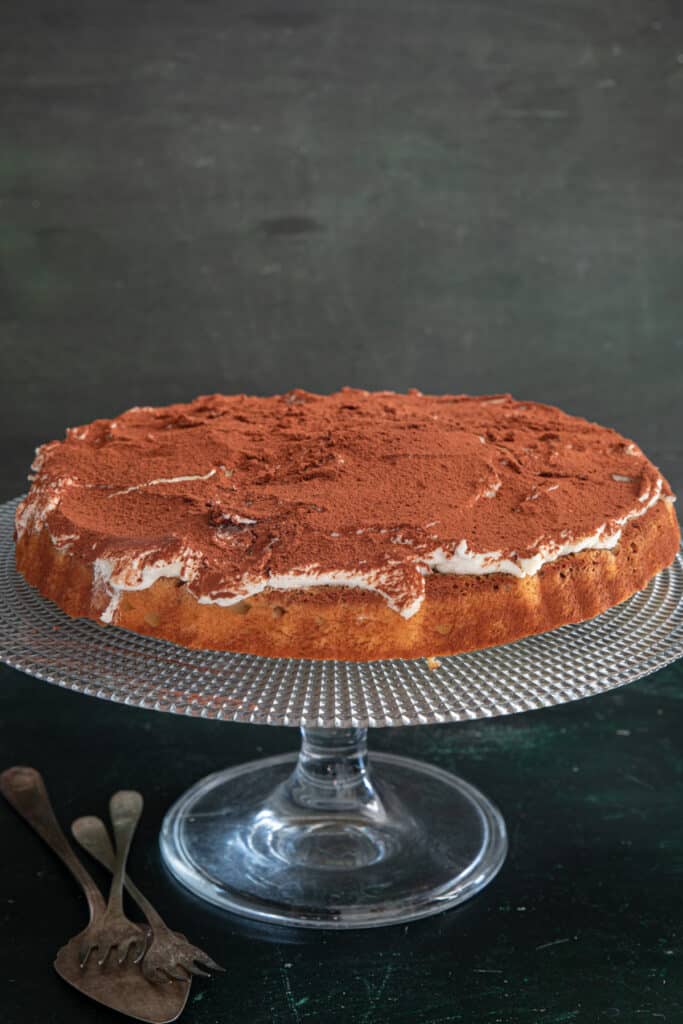 Tiramisu crostata on a glass cake plate.