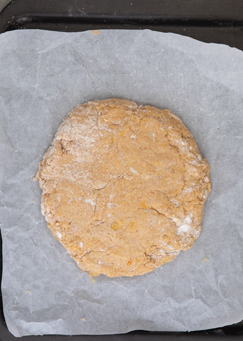 Patting the dough into a circle on parchment paper.