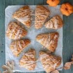 Frosted pumpkin scones on a piece of parchment paper.