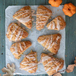 Frosted pumpkin scones on a piece of parchment paper.